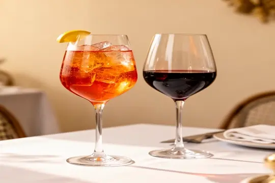 Aperol Spritz und Glas Rotwein auf gedecktem Tisch